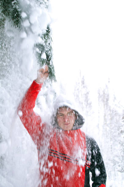 istock young man in a red sweater showering snow from pine branches in the forest 1130348385