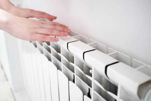 istock girl warms hands near a radiator 1130350894
