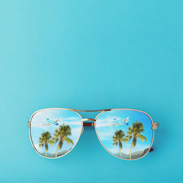 istock Sunglasses with palm trees, a plane and mountains reflected in them. Concept on the theme of vacation and travel with copy space 1130351042