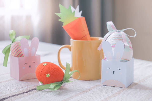 istock Yellow mug, Happy Easter handmade paper bunny rabbits and colorful handcrafted eggs with ribbon bow. Decoration Concept 1130351277