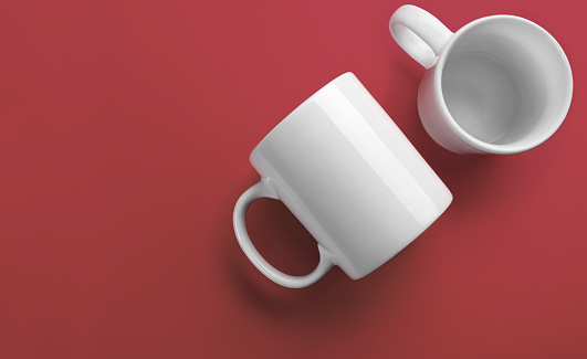 Side and top of white mugs on coral color background