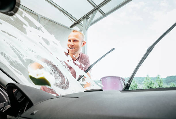 istock Man washes his car windshield window inside the car camera view 1130357728