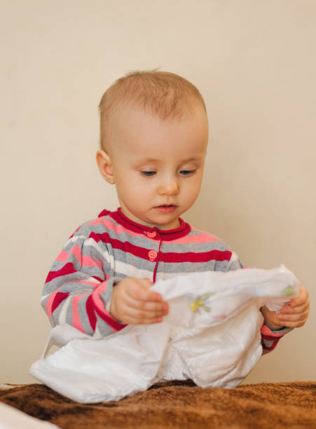 istock baby holding a nappy in hand and looking 1130359331