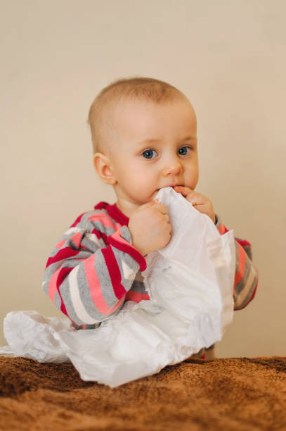 istock baby holding a nappy in mouth and looking 1130359352