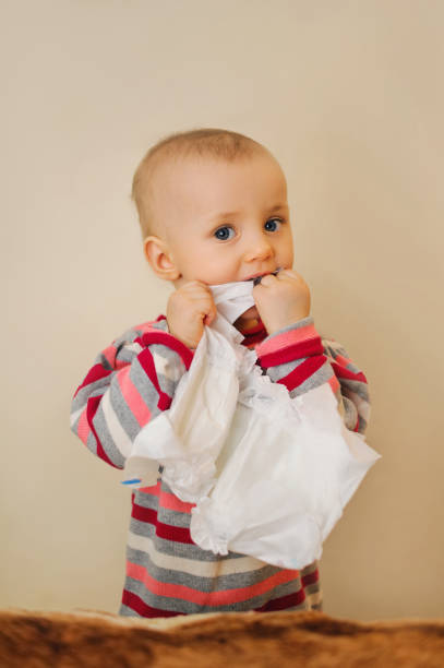 istock baby holding a nappy in mouth and looking 1130359944