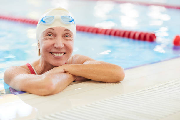 heureuse femme senior dans la piscine - active seniors retirement enjoyment swimming pool photos et images de collection