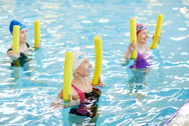 femmes matures qui travaillent dans l’eau - water aerobics swimming pool exercising sport photos et images de collection