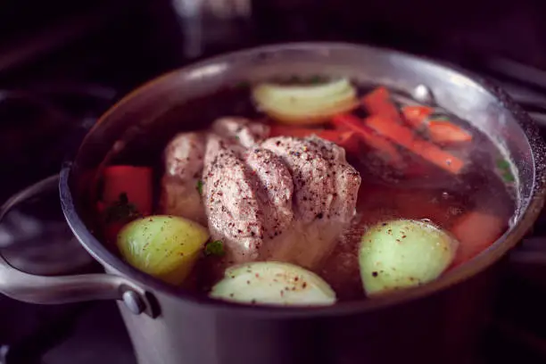 preparing a soup with a big part of meat, onions and carrots in a saucepan