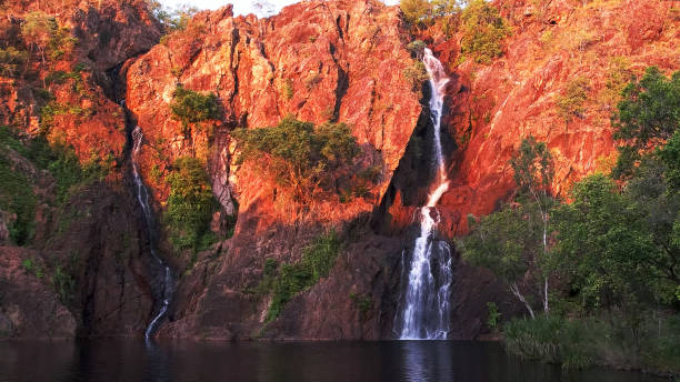 definir o sol transforma as falésias na wangi cachoeiras no parque nacional de litchfield um vermelho brilhante - non urban scene standing water waterhole landscape - fotografias e filmes do acervo