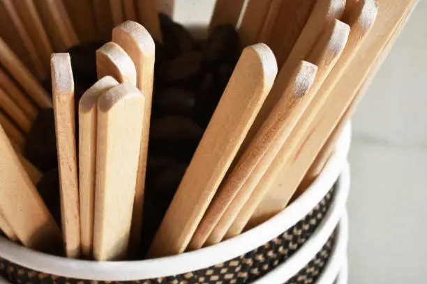 A close up image of several wooden coffee stir sticks in a disposable cup.