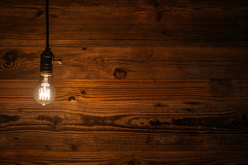 an old vintage light bulb against a grunge wooden wall background