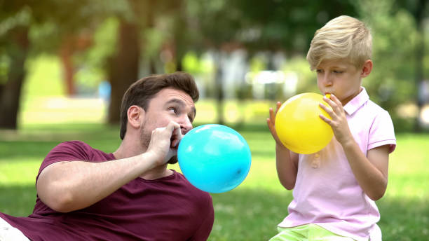 padre e hijo volando globos, divirtiéndose juntos, recreación despreocupada - balloon blowing inflating child fotografías e imágenes de stock