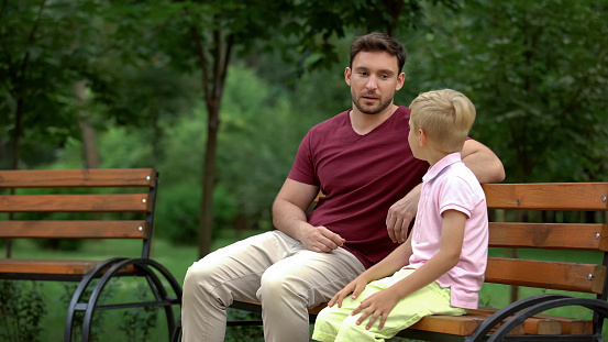 Conversation between father and son in park, loving dad giving advices to kid