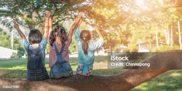 Children Friendship Concept With Happy Girl Kids In The Park Having Fun Sitting Under Tree Shade Playing Together Enjoying Good Memory And Moment Of Student Lifestyle With Friends In School Time Day Stock Photo - Download Image Now
