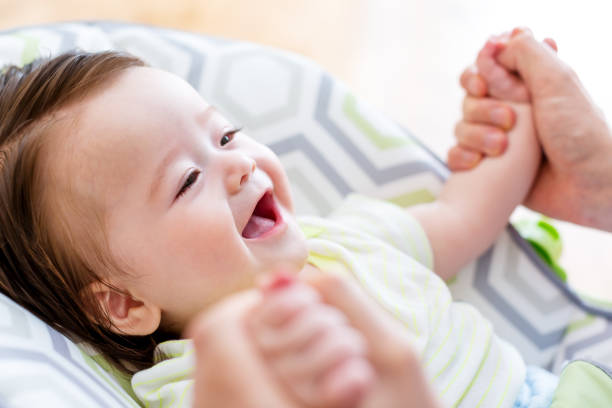 Happy 5-month baby boy receiving massage therapy in pediatric clinic. Manual therapist manipulates childs's arms