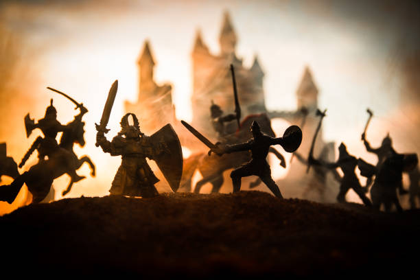istock Medieval battle scene with cavalry and infantry. Silhouettes of figures as separate objects, fight between warriors on sunset foggy background. 1130384363