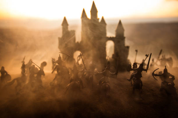 istock Medieval battle scene with cavalry and infantry. Silhouettes of figures as separate objects, fight between warriors on sunset foggy background. 1130384369