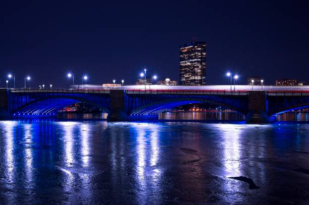 the red t moving across the longfellow bridge with the hancock building and frozen charles river - boston charles river skyline massachusetts imagens e fotografias de stock