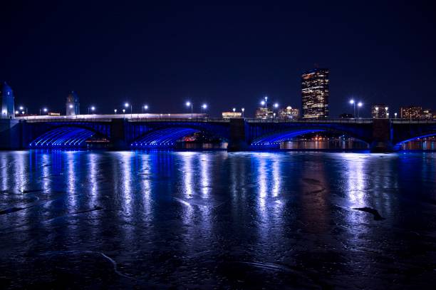 the red t moving across the longfellow bridge with the hancock building and frozen charles river, - boston charles river skyline massachusetts imagens e fotografias de stock