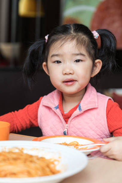 istock Cute baby girl eating spaghetti 1130402850