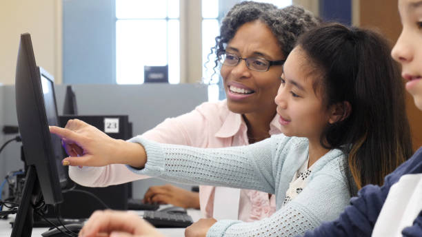 istock Librarian helps little girl with computer research 1130408117