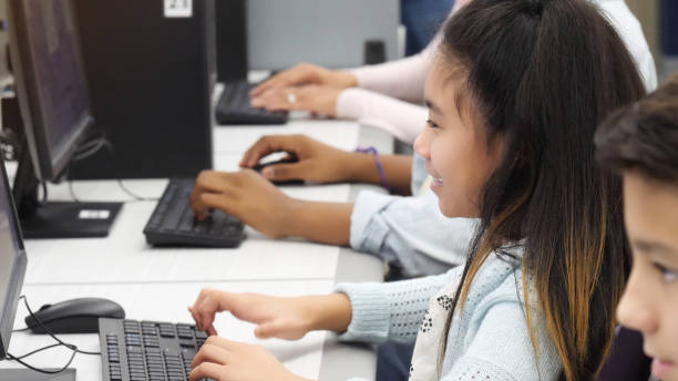 istock Elementary age girl works in busy computer lab 1130408134
