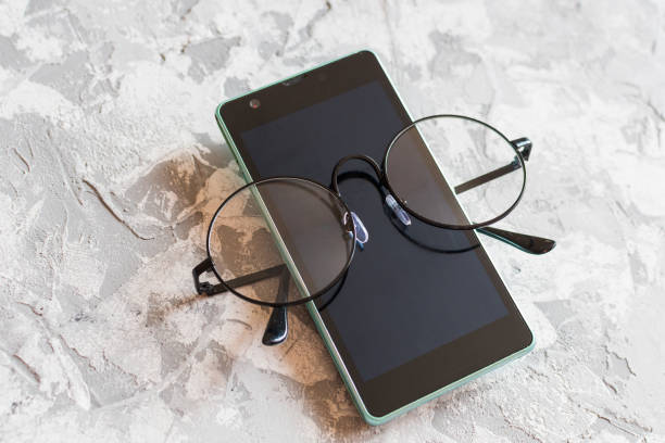 istock phone and glasses on grey background 1130417418