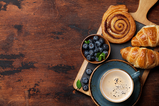 Coffee, croissants and berries breakfast. On wooden table. Top view with copy space for your text