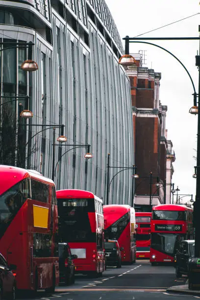 Photo of Red double decker buses driving down Oxford Street, London