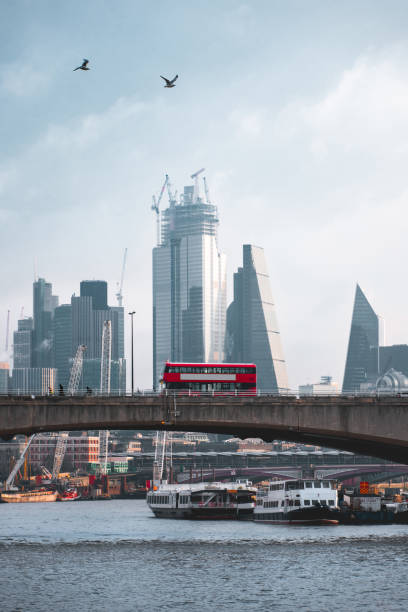 iconic red double decker bus crossing waterloo bridge, with the city of london in the background - crane skyline uk tower of london imagens e fotografias de stock