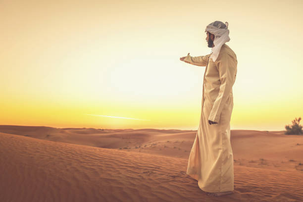 istock Arab man standing on the dunes and aiming towards the sunset 1130419028