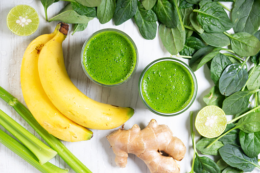 Fresh green smoothie with spinach, banana and ginger on wooden background