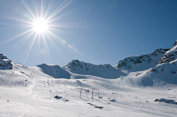 istock Ski lift at high altitude resort, sun with flare 113041996