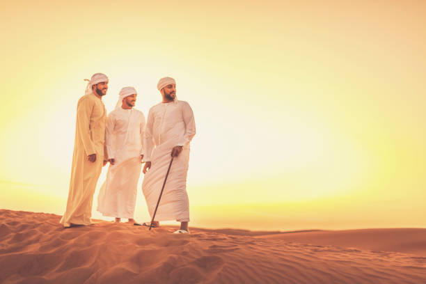 amis arabes appréciant coucher de soleil sur les dunes de sable - middle eastern ethnicity sheik wealth men photos et images de collection