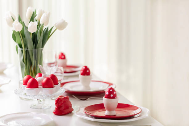 joyeuses pâques. decor et réglage de la table de la table de pâques est un vase avec des tulipes blanches et des plats de couleur rouge et blanche. pâques colorés oeufs à pois blancs. - retro revival food easter napkin photos et images de collection