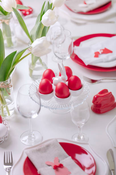 istock Happy easter. Decor and table setting of the Easter table is a vase with white tulips and dishes of red and white color. Easter colored eggs with white polka dots. 1130422423