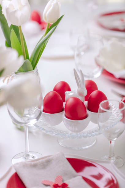 istock Happy easter. Decor and table setting of the Easter table is a vase with white tulips and dishes of red and white color. Easter colored eggs with white polka dots. 1130422427