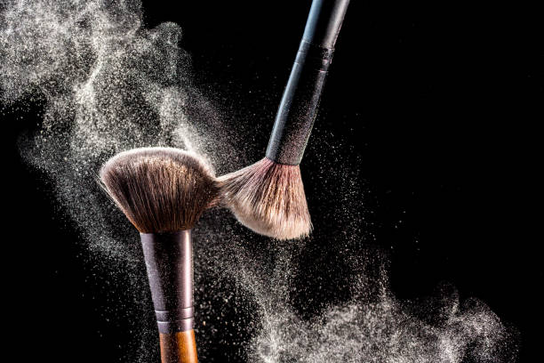 compõem cosméticos pincéis com explosão de blush em pó sobre fundo preto. conceito de moda ou cuidados da pele. - face powder exploding make up dust - fotografias e filmes do acervo