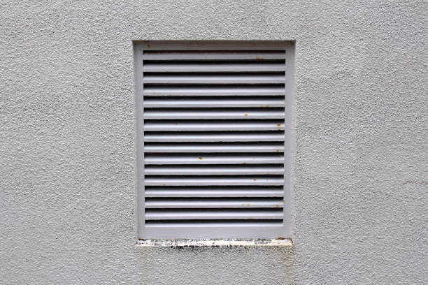 istock Grey metal protection bars on large industrial fan exit with partially rusted parts mounted on light grey wall on side of building 1130423867
