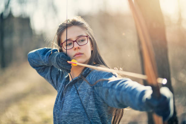 Teenage girl shooting a bow Teenage girl drawing a bow outdoors on winter day.
Nikon D850. bow and arrow photos stock pictures, royalty-free photos & images