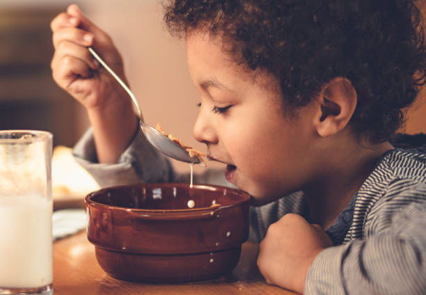 istock Cute African American boy eating cereal for breakfast at home. 1130429078