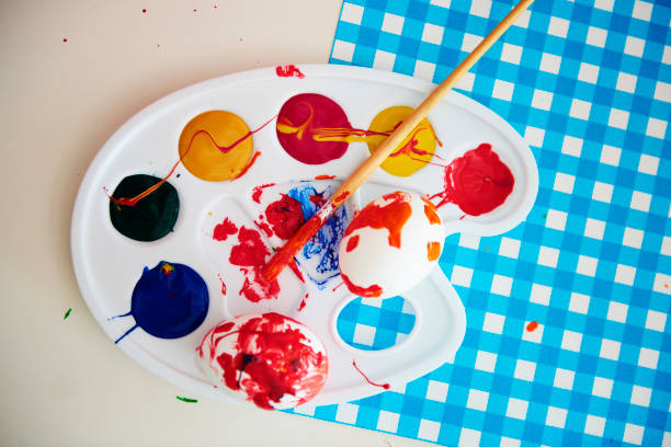 Palette with colorful paints, paintbrush and easter egg
