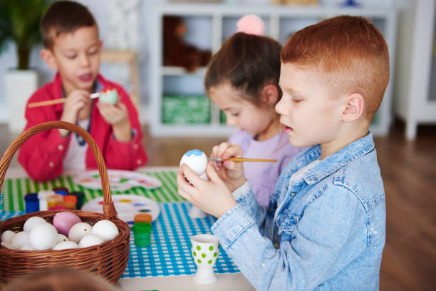 istock Side view of focused boy painting easter egg 1130433312