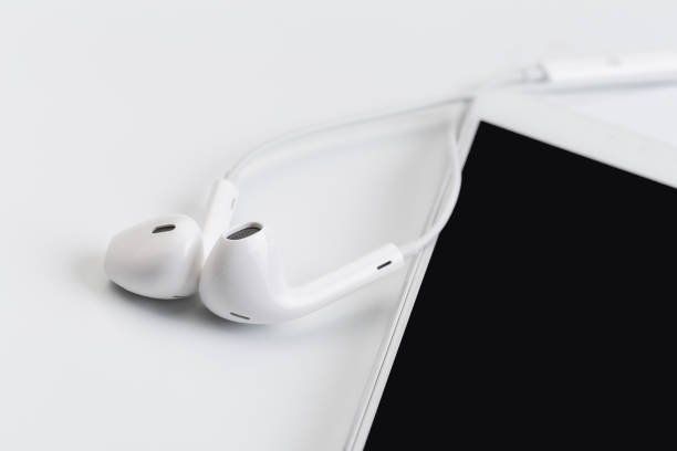 istock white earphones on white keyboard with phone 1130435038