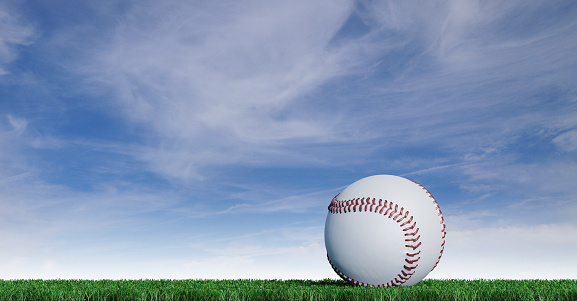 Baseball put on a well-cut lawn with a blue sky background