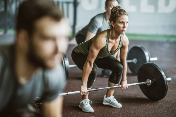 mulher de construção muscular exercício deadlift em uma aula de treinamento em uma academia. - sports training muscular build women body care - fotografias e filmes do acervo