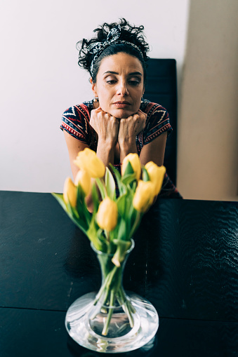 Moody woman staring at bouquet of yellow tulips