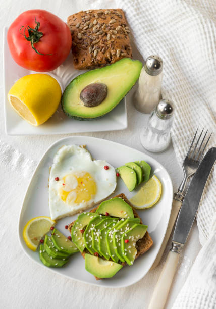 istock sandwich with avocado, egg, sesame, lemon, tomato, spices, fork, knife, avocado slices, half of avocado and lemon 1130440854