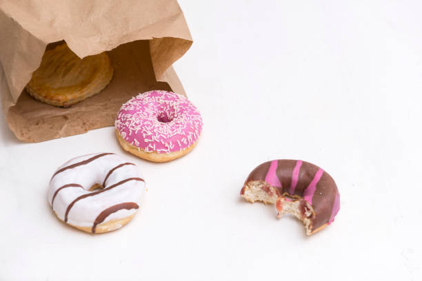 istock donuts with white, pink and chocolate icing, 3 donuts, 1 bitten donut on white background 1130440873