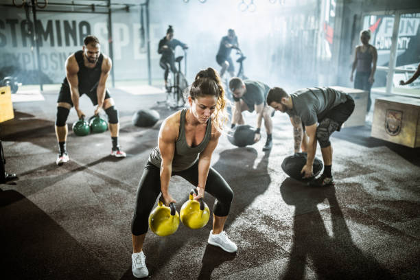 un grande gruppo di atleti che esercitano la forza dell'allenamento incrociato in palestra. - cross training foto e immagini stock